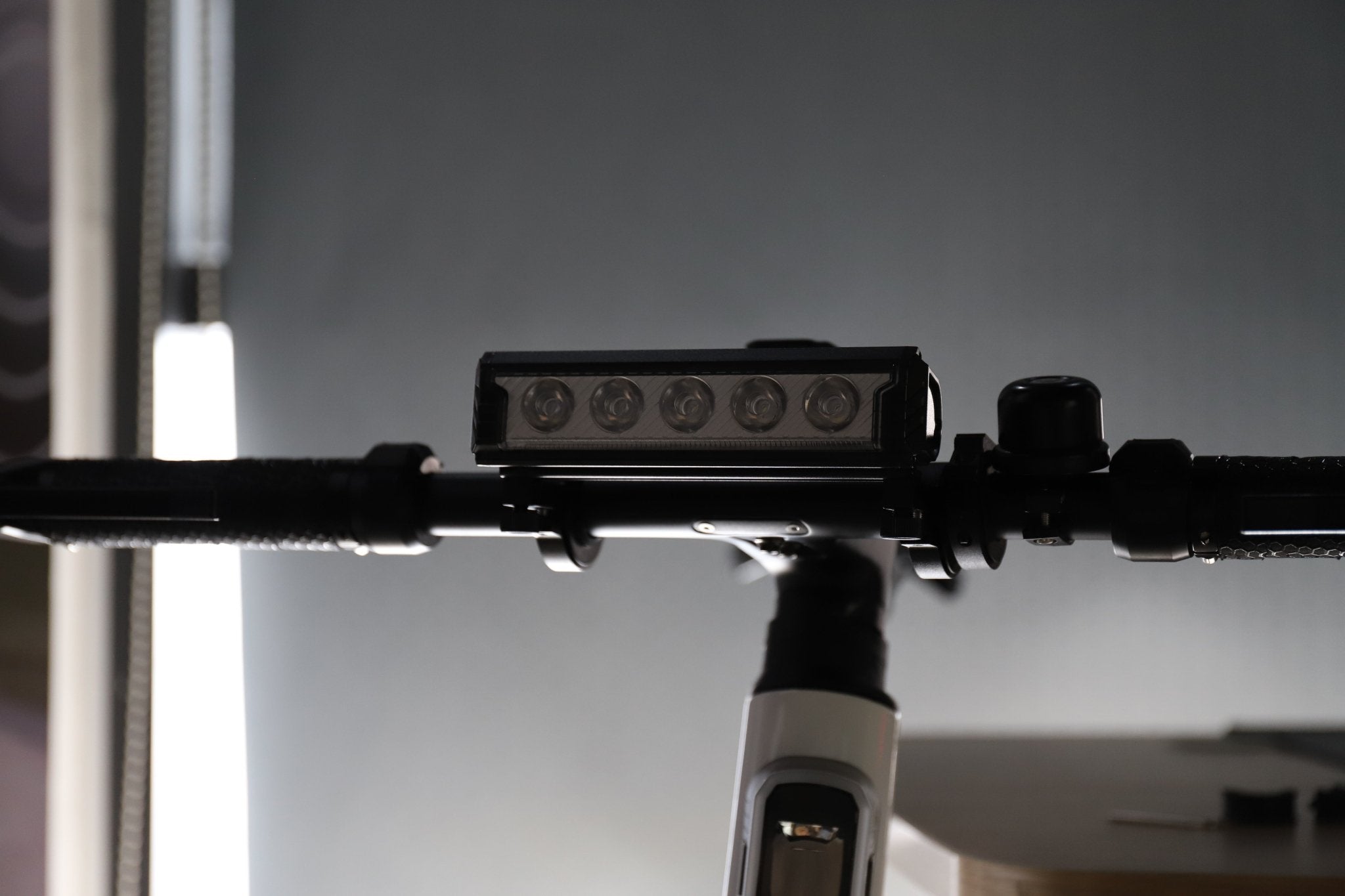 Multi-LED bike front light mounted on a handlebar in a studio scene with the lenses visible