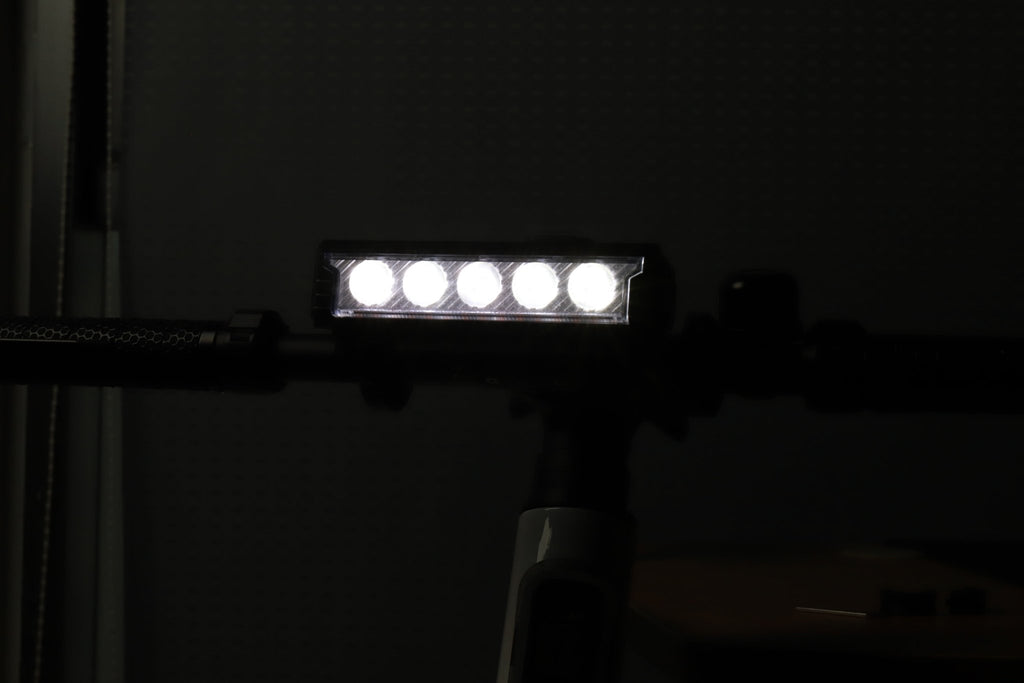 Multi-LED bike front light shining white from a handlebar-mounted position