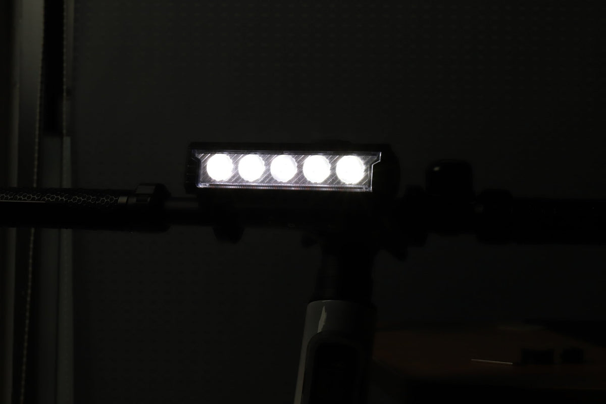 Multi-LED bike front light shining white from a handlebar-mounted position