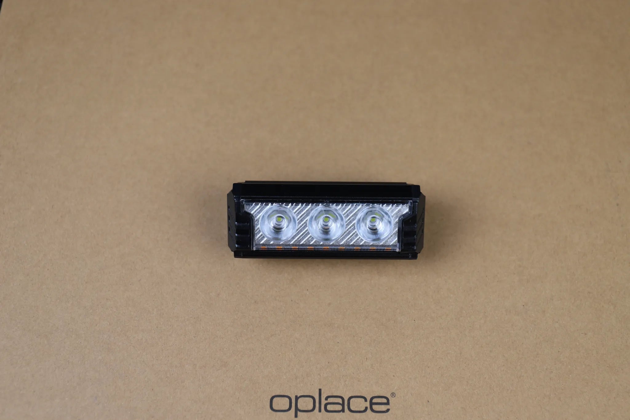 Compact multi-LED USB-C rechargeable bike front light shown at an angle on a beige background