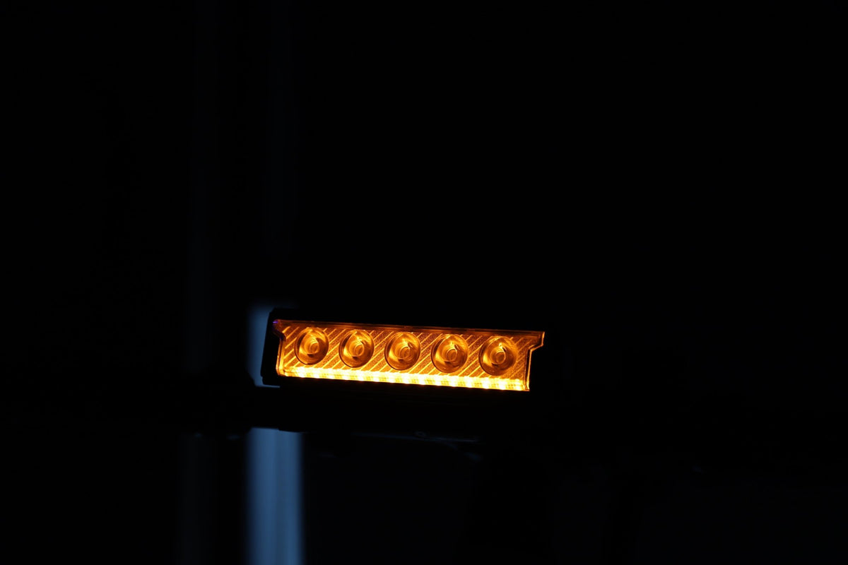 Multi-LED bike front light glowing amber on a handlebar in a dark scene