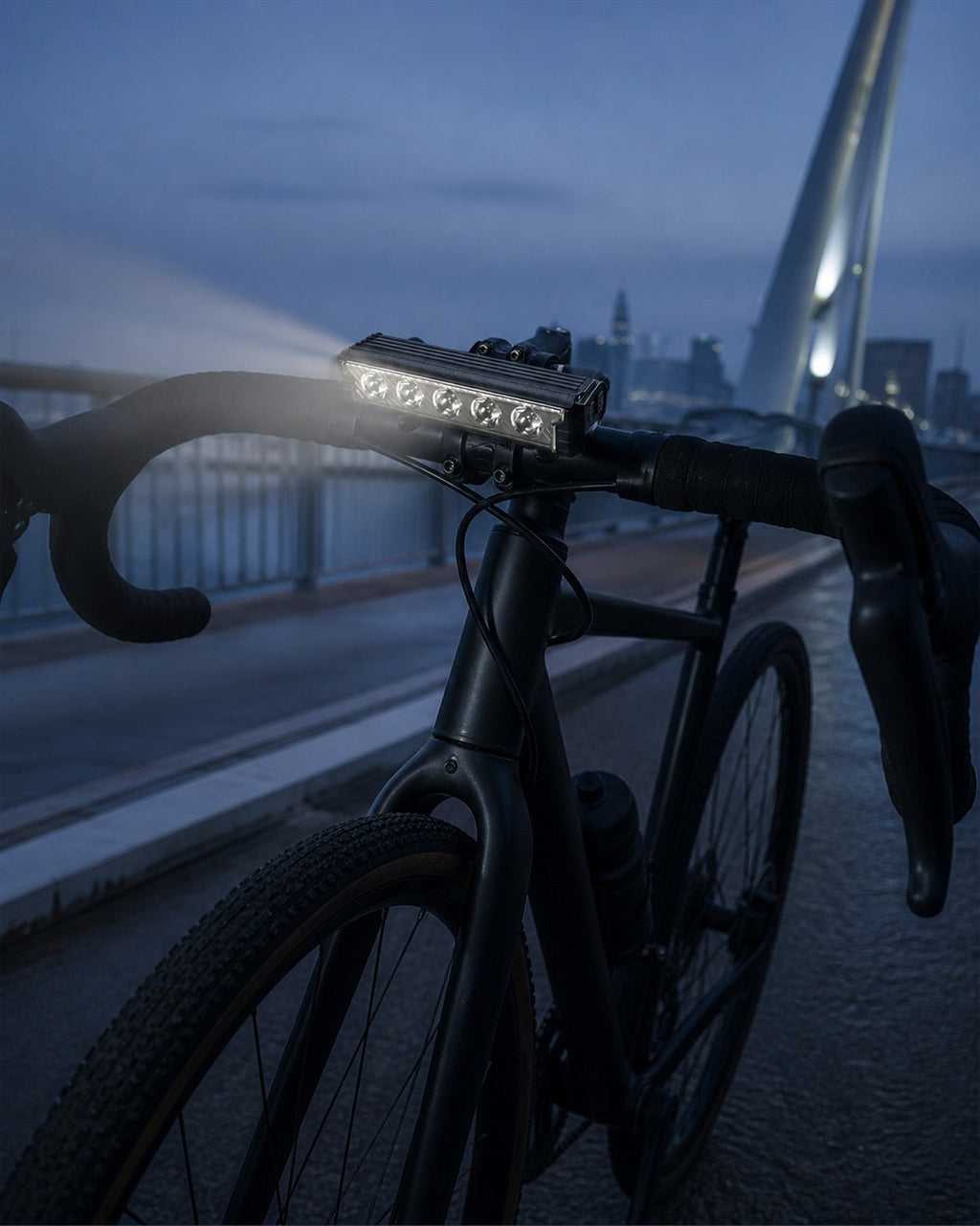 Multi-LED bike front light mounted on a road bicycle at dusk near a bridge