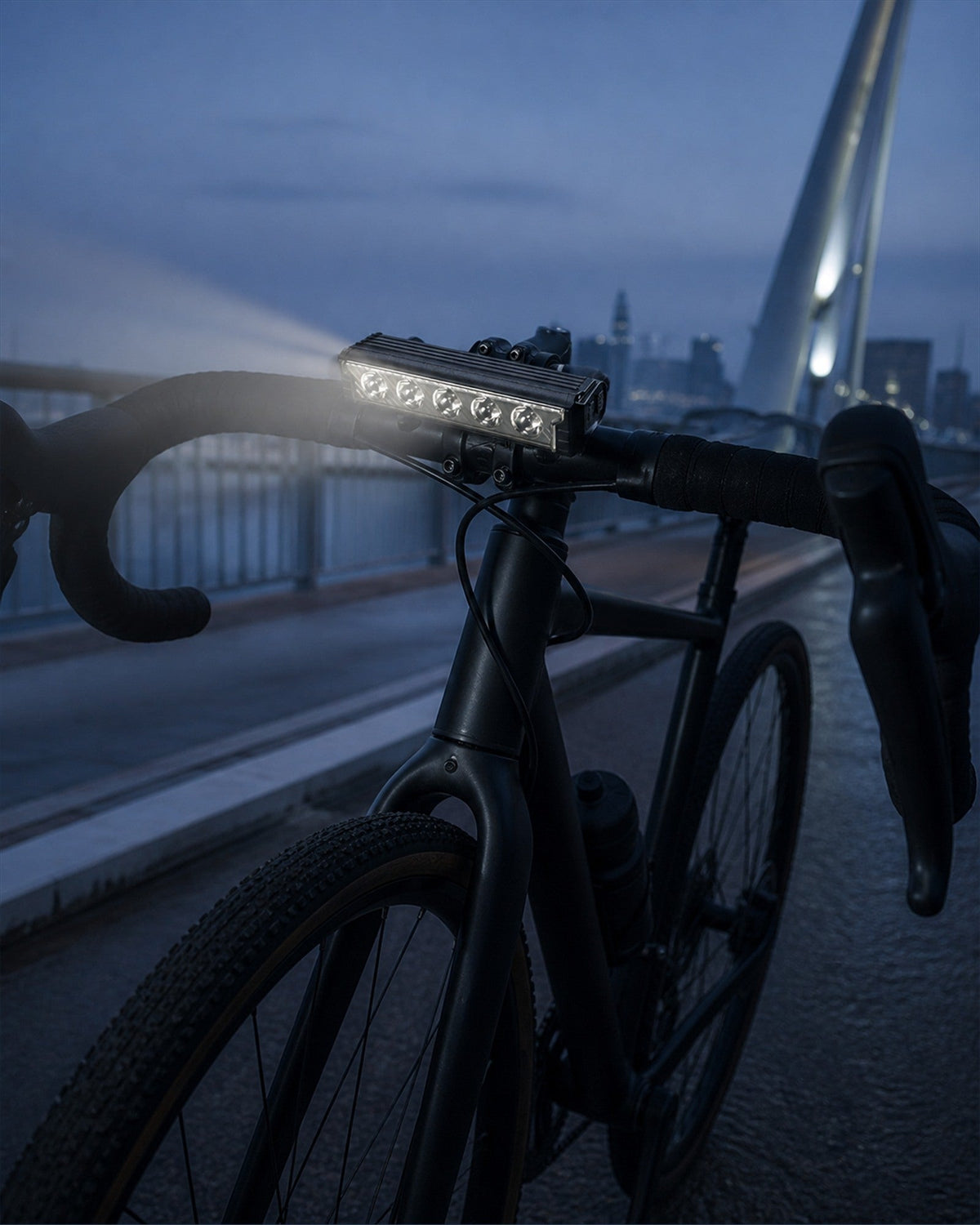 Multi-LED bike front light mounted on a road bicycle at dusk near a bridge