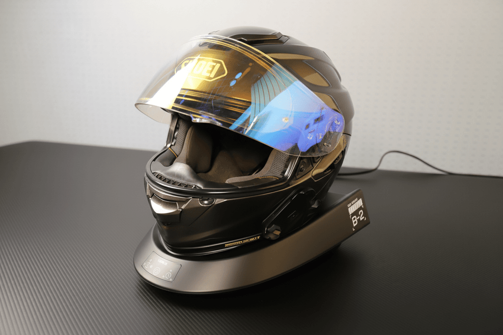 Smart Helmet and Gear Dryer Pro beneath a reflective motorcycle helmet on a neutral background