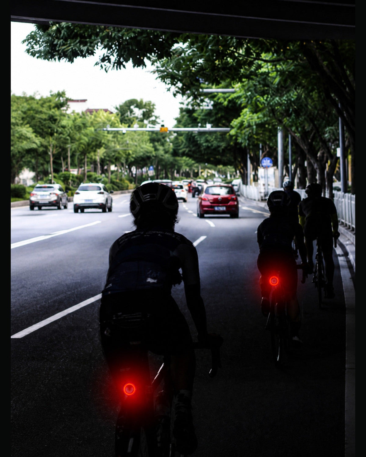 Cyclists riding on a city road with red rear lights visible in the distance