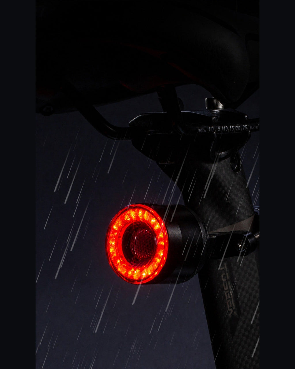 Round RGB halo bike light glowing red beneath a bicycle saddle in the rain