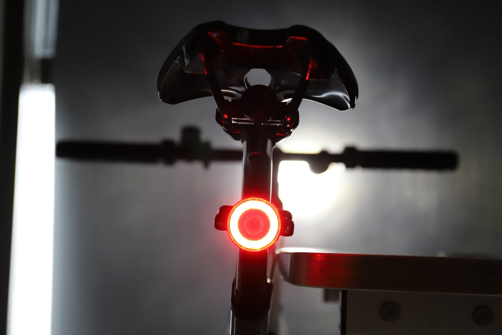 Rear bicycle view with a bright red halo light glowing beneath the saddle