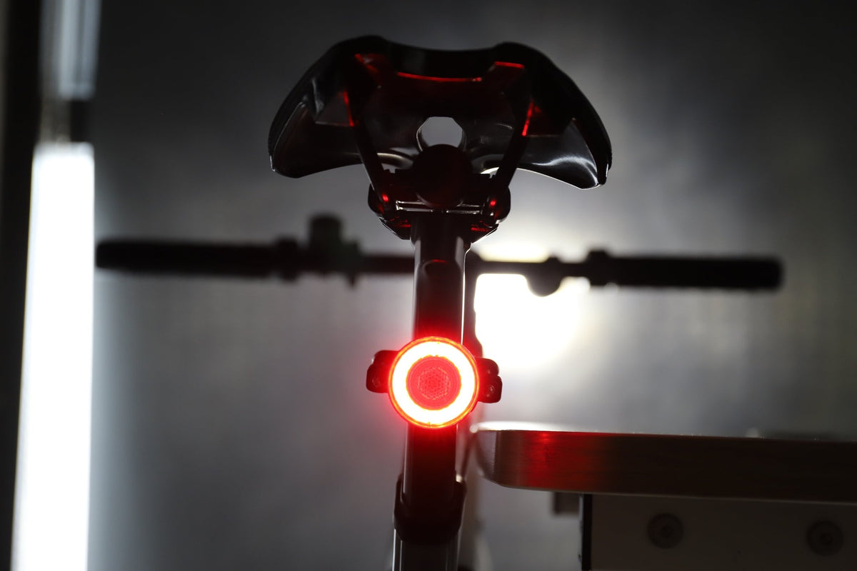 Rear bicycle view with a bright red halo light glowing beneath the saddle