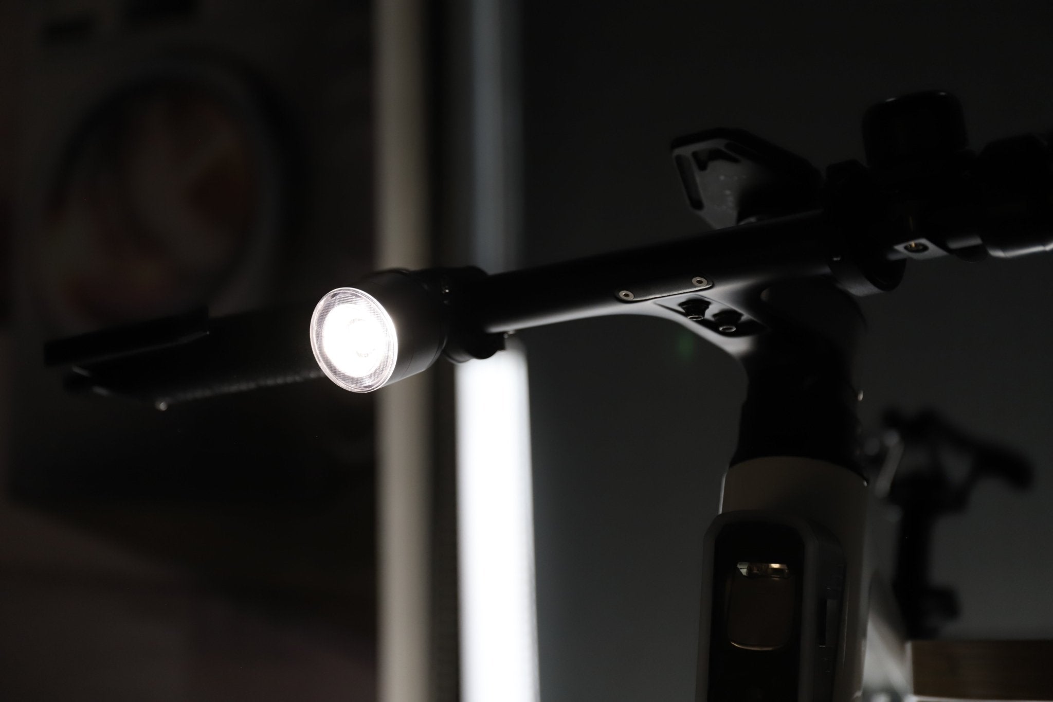 Close view of a handlebar-mounted bike light casting a white beam