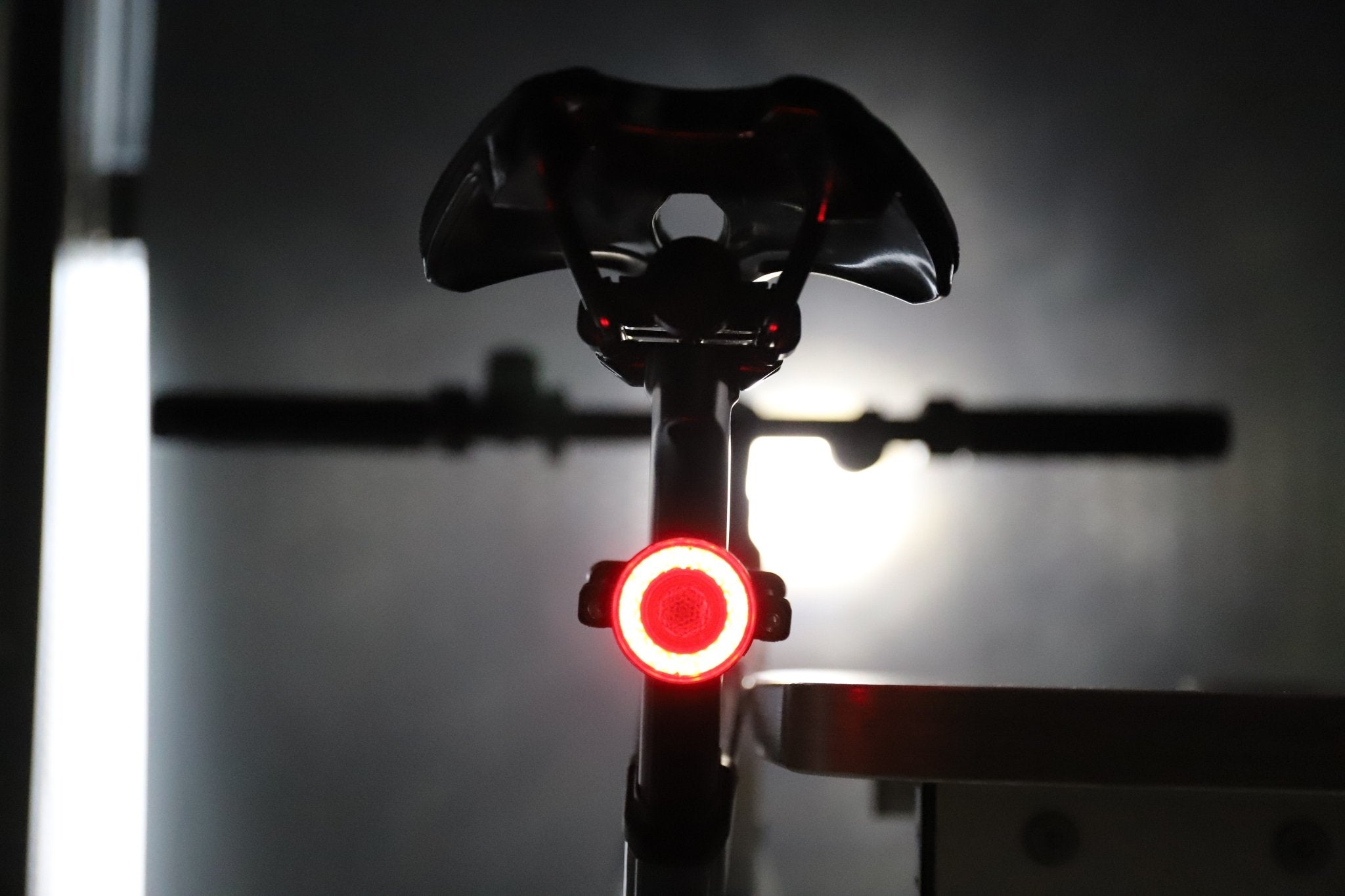 Rear bicycle view with a red halo light glowing beneath the saddle