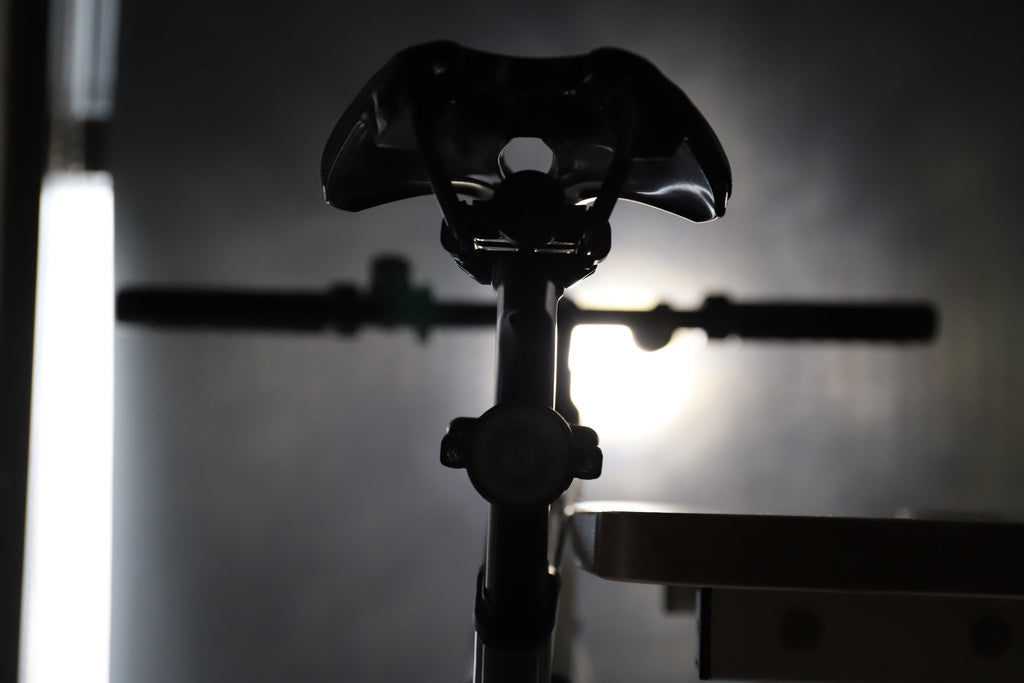 Rear bicycle view with a circular halo light glowing beneath the saddle