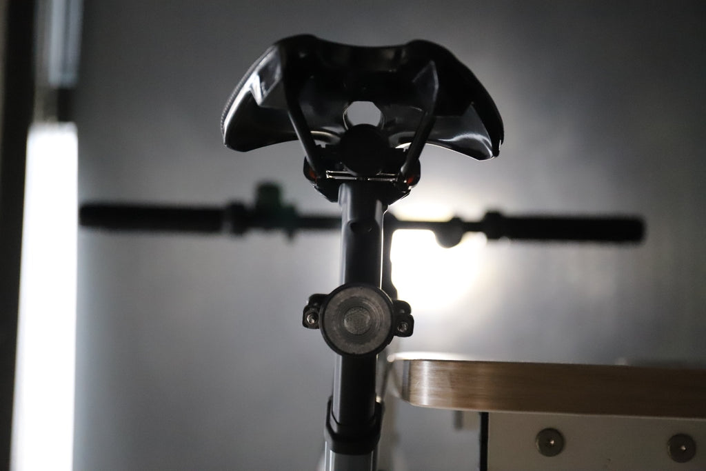 Rear bicycle view with an unlit round light mounted below the saddle