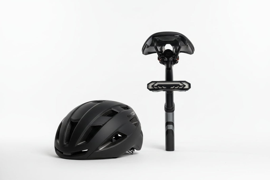 Bike helmet beside a seatpost-mounted OPlace alarm tail light on white